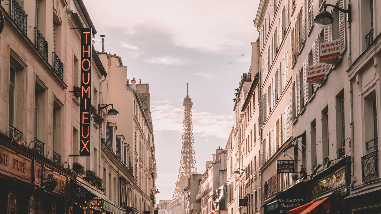 Rue parisienne avec circulation et tour Eiffel au loin